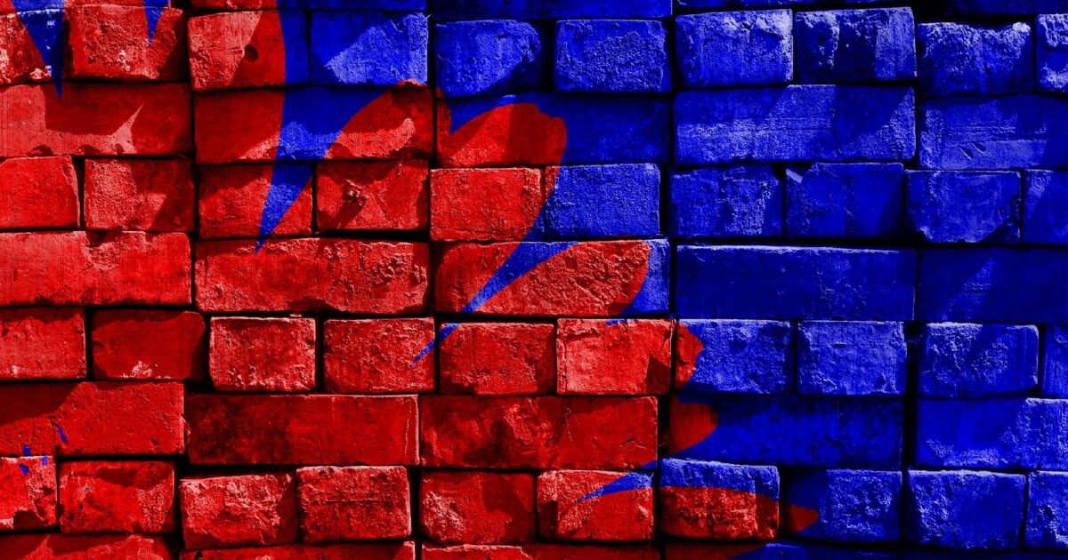 mur en brique peint en bleu. Rosace rouge dans l'angle de gauche.