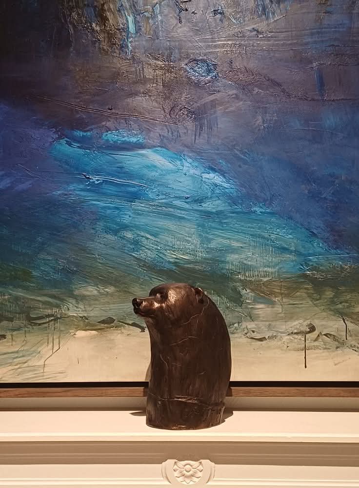 Sculpture de tête d'ours brun en bronze devant une peinture à l'huile de tonalité bleue