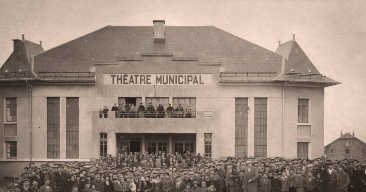 Photo en noir et blanc, foule d'adultes en enfants qui posent devant le théâtre municipal