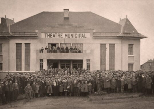 Photo en noir et blanc, foule d'adultes en enfants qui posent devant le théâtre municipal