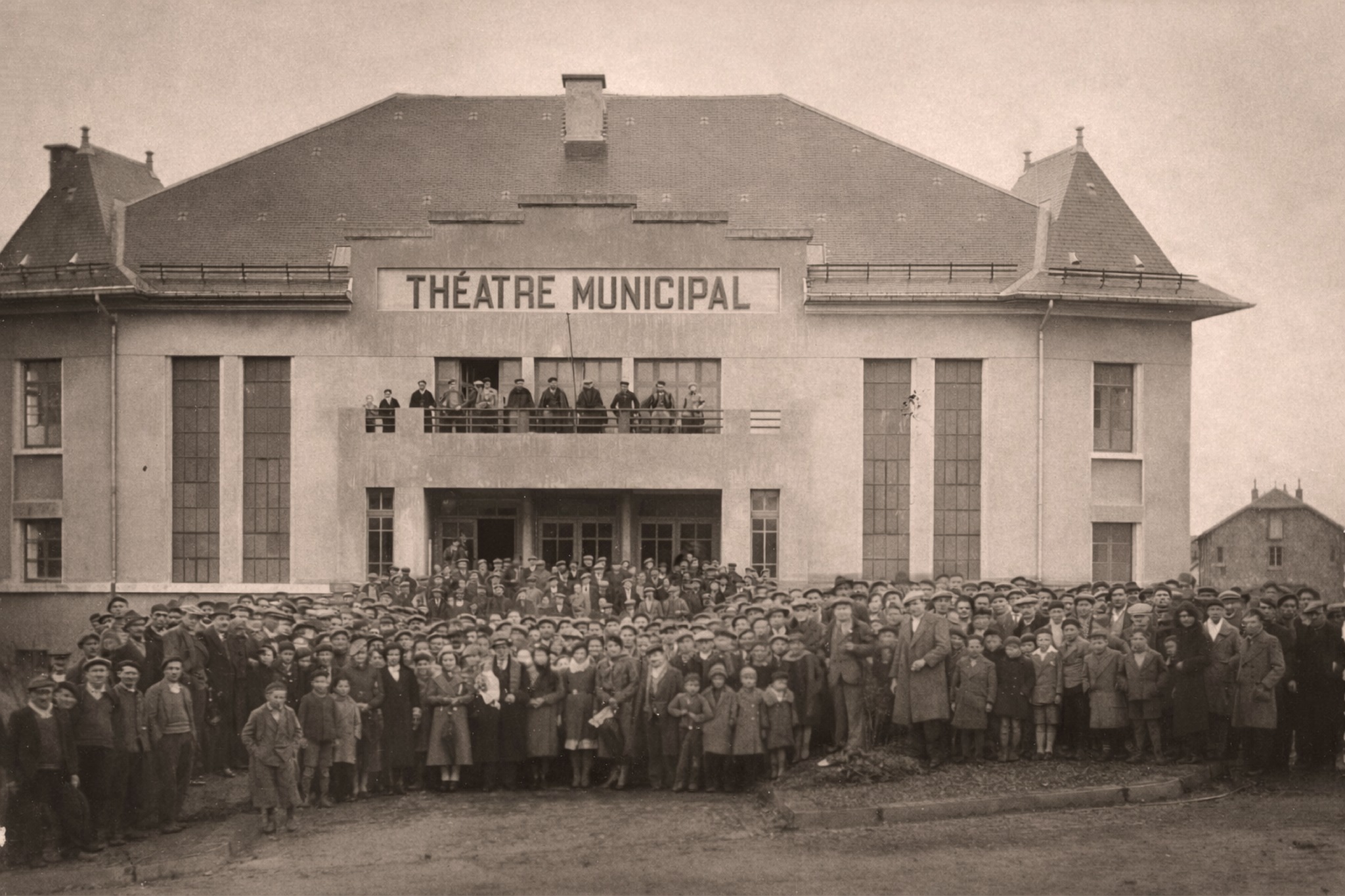 Photo en noir et blanc, foule d'adultes en enfants qui posent devant le théâtre municipal