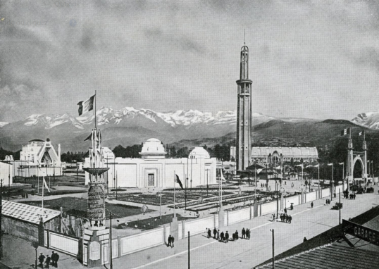 Photo en noir et blanc représentant l'exposition universelle de 1925 dont la tour Perret en premier plan et un panorama de montagnes en second plan